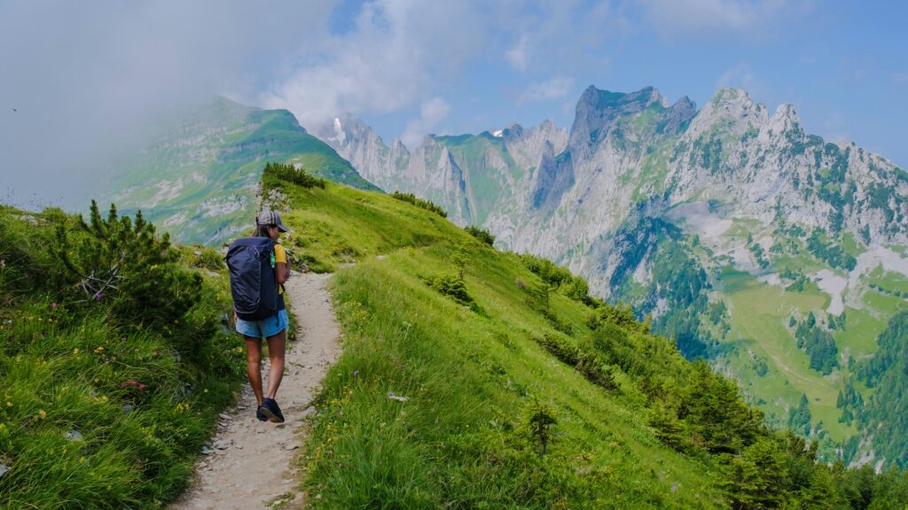 women hiking in the Swiss Alps mountains at summer vacation with a backpack and hiking boots